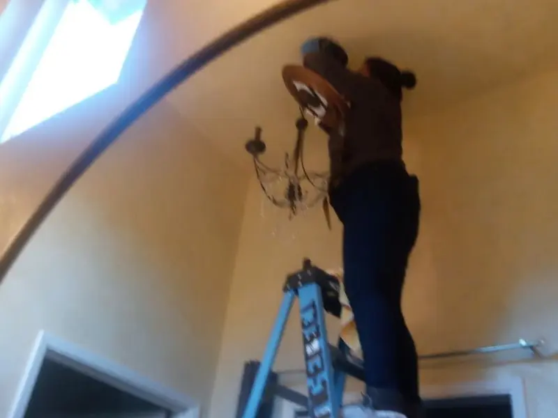 Electrician installing a chandelier in a Angleton residence